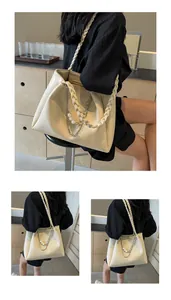 Close-up of cream tote bag with woven shoulder strap and decorative pearl chain detail