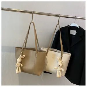 Detail of minimalist tote bags with cute bunny pendants and printed fashion logo text