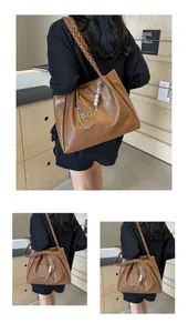 Close-up of brown tote bag featuring a braided shoulder strap and pearl chain detail