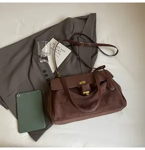 Dettaglio della borsa vintage marrone opaca con chiusura dorata su sfondo in tessuto bianco
