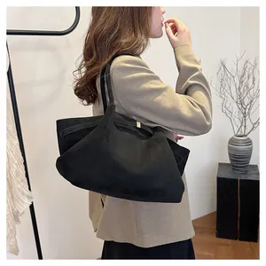Modella indossa borsa tote in pelle scamosciata nera con fibbia dorata in stile minimalista