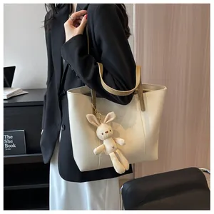 Detail of off-white leather tote bag with brown straps and cute plush rabbit charm