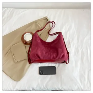 Detail view of burgundy suede hobo bag with gold hardware on minimalist white fabric