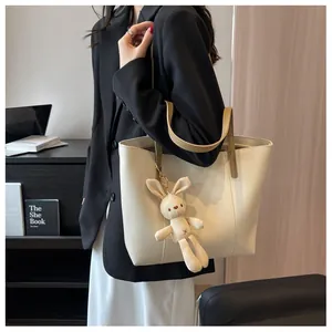 Detailed shot of a beige leather tote bag with brown straps and plush bunny pendant