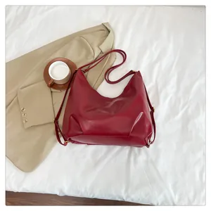 Close-up of matte dark red faux leather shoulder bag with pleated texture and gold hardware