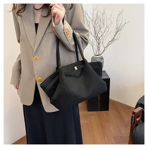 Dettaglio borsa tote in pelle scamosciata nera con chiusura in metallo per il lavoro