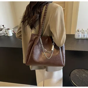 Close-up of a dark brown vintage tote bag with woven strap and pearl chain decoration
