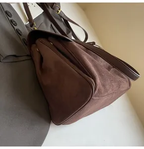 Dettaglio della borsa a spalla in pelle scamosciata marrone con texture e ampia capacità