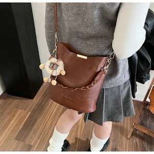 Detailansicht braune Eimertasche mit Webgriff und Löwen-Anhänger am Model getragen