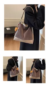 Close-up of brown faux suede bucket bag with white polka dots and cute bear pendant