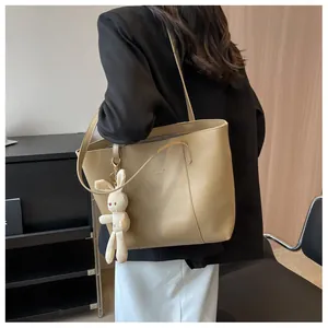 Close-up of beige leather tote bag with cute white rabbit charm on a stylish model