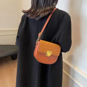 Borsa a sella marrone in finta pelle e camoscio con fibbia dorata su modella in cappotto nero