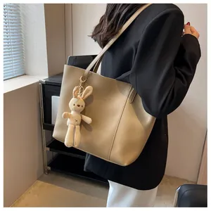 Detail of beige large capacity tote bag with plush rabbit charm and Fashion trend text