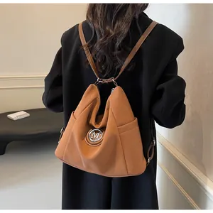 Rückansicht eines Models mit braunem Mehrzweck-Rucksack und silbernem M-Logo-Detail