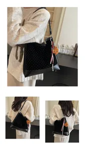 Detailed view of black polka dot tote bag with plush bear charm and striped strap accent