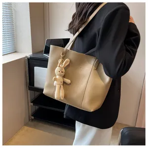 Detail of beige faux leather tote bag with Fashion Trend print and plush bunny charm