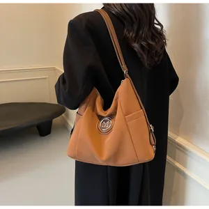 Detailansicht der braunen Hobo-Tasche mit Seitentasche und M-Logo aus robustem Nylon
