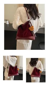 Detail of burgundy suede shoulder bag with studded dots and plush bear keychain charm