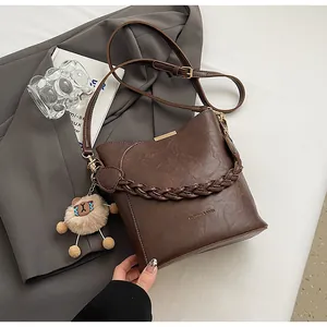 Detail der dunkelbraunen geflochtenen Eimertasche mit Lederband und Schaf-Anhänger