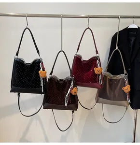 Detail view of four suede bucket bags in black, brown, wine red and apricot colors