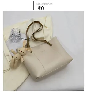 Detailed view of beige tote bag with brown handles and a cute plush rabbit charm