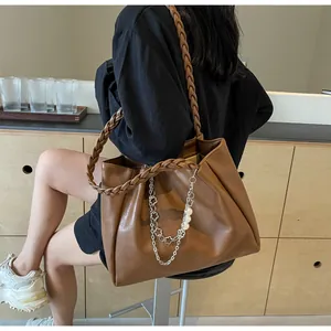 Detail of caramel tote bag with woven handles and pearl chain charm for daily commute