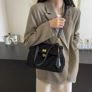 Borsa a tracolla classica in camoscio nero con chiusure dorate indossata da modella