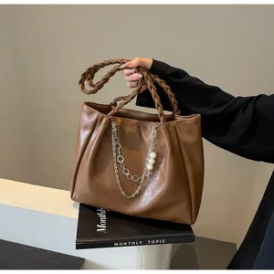 Detailed macro view of brown PU leather tote with woven handle and pearl metal chains