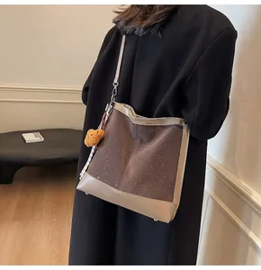 Close-up of brown suede bucket bag with white polka dots and cute bear pendant