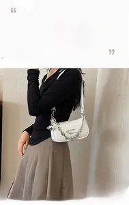 Detail of white embossed leather handbag featuring silver chunky chain and round charm
