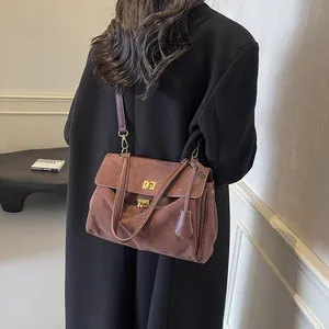 Borsa a tracolla in pelle scamosciata marrone con chiusura dorata indossata da una modella