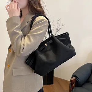Grande borsa tote nera opaca con fibbia dorata indossata da modella in blazer color kaki