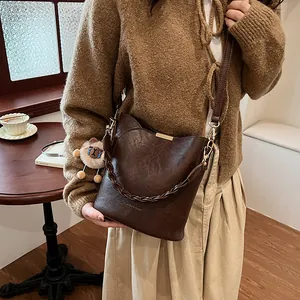 Retro dunkelbraune gewebte Beuteltasche mit Löwenanhänger präsentiert im Café