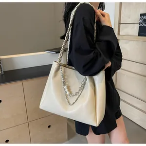 Detail view of beige leather tote bag with braided straps and decorative pearl chain