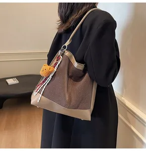 Close-up of brown suede bucket bag with white polka dots and plush bear charm accessory