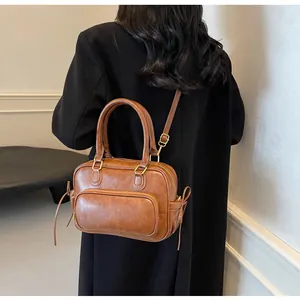 Detail view of a vintage brown leather Boston bag with side drawstring and front zipper pocket