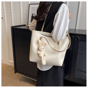 Close-up of cream tote bag stitching with cute plush rabbit charm on side
