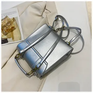 Détail d'un sac à dos argenté en cuir PU avec ferrures dorées sur fond de tissu ivoire