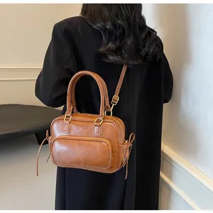 Brown vintage faux leather handbag with tassel details and adjustable strap on model