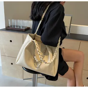 Detail of cream white tote bag featuring woven handles and pearl star chain ornament