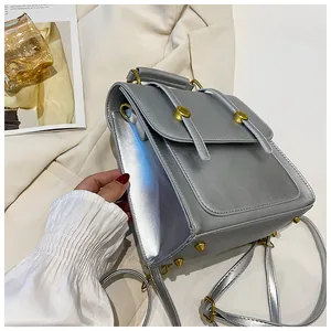 Détail d'un sac à dos gris argenté avec boucles dorées et rivets de protection de fond