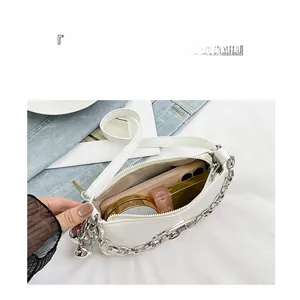 Detail showing the spacious interior of a white shiny shoulder bag with items inside