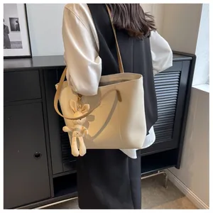 Macro detail of creamy white tote bag featuring smooth PU leather and cute rabbit charm