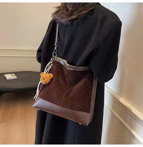 Detail of dark brown suede tote bag with white polka dots and cute bear pendant charm