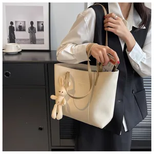 Detail view of cream PU leather tote bag with contrast strap and plush rabbit charm
