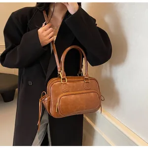 Close-up of a vintage brown leather Boston bag with gold hardware and shoulder strap