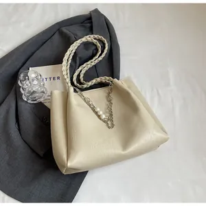 Detail of cream tote bag with braided handle, silver chain and pearl decorations