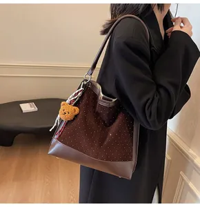 Detail of brown suede bucket bag with white polka dots, plush bear and striped scarf
