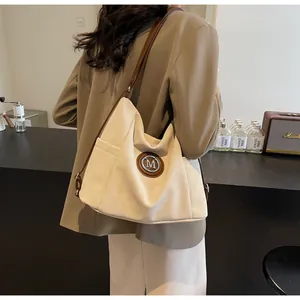 Detail der minimalistischen cremefarbenen Segeltuchtasche mit braunem Lederbesatz und M-Logo