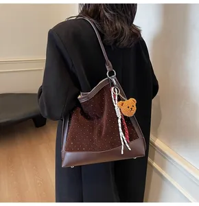 Detailed view of brown suede tote bag with silver studs and cute bear pendant charm